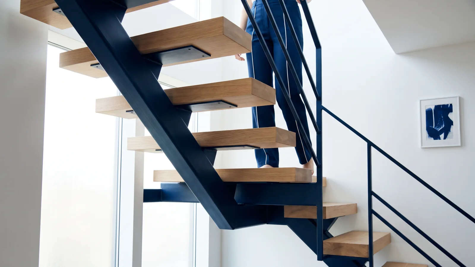 Holztreppe oder Stahltreppe: Die richtige Wahl für Ihr Zuhause 1 Eine moderne Treppe mit Holzstufen und dunklem Stahlgeländer, die die Wahl zwischen Holztreppe oder Stahltreppe in einem Haus zeigt.